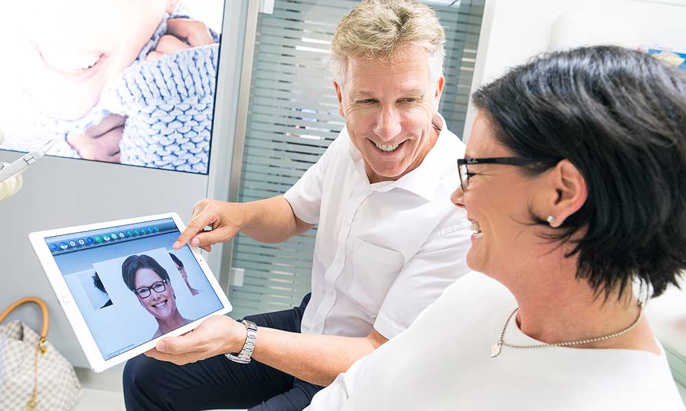 Arzt zeigt seiner Patientin auf einem Tablet Fotos von ihr