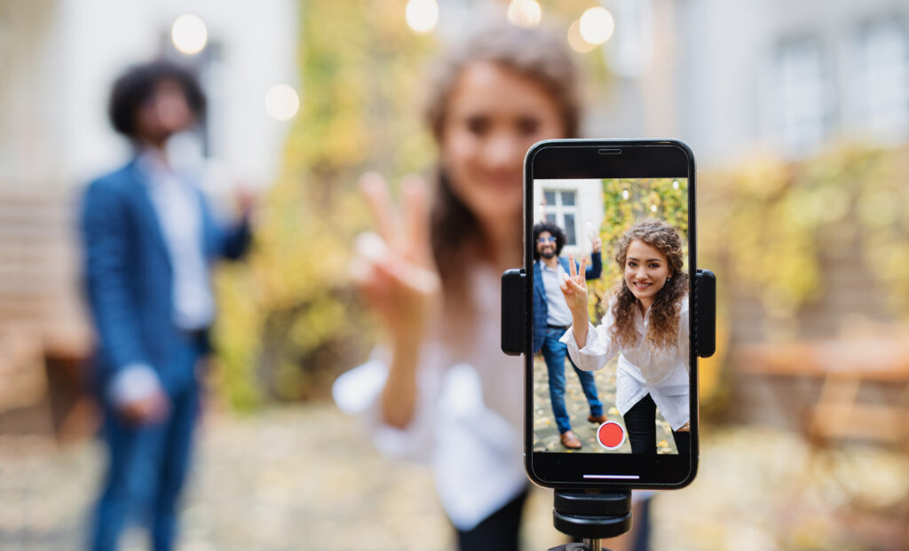 Zwei junge Menschen nehmen ein TikTok-Video auf: TikTok als Kommunikationsmedium für Unternehmen